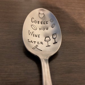 May include: A silver spoon with the text "Coffee Now Wine Later" engraved on it. The spoon also has a coffee cup, coffee bean, wine glass, and corkscrew engraved on it.