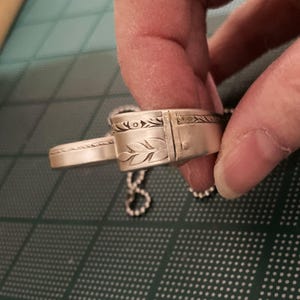 May include: Silver pendant necklace with a detailed leaf design and a chain.