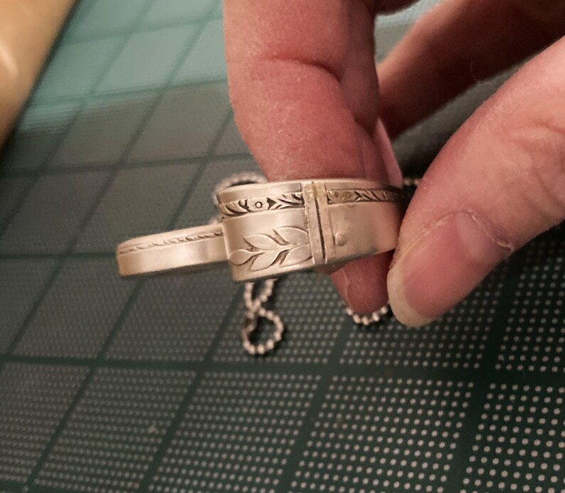 May include: Silver pendant necklace with a detailed leaf design and a chain.