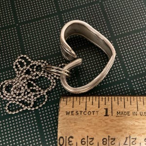 May include: A silver heart-shaped pendant necklace made from a repurposed spoon. The necklace is approximately 1 inch in length and features a silver ball chain.