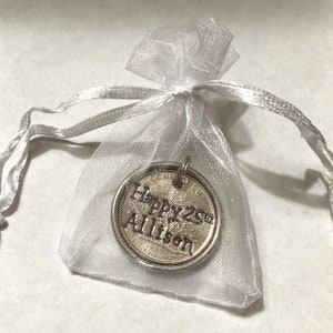 May include: A silver-colored coin pendant inside a sheer white organza gift bag. The coin has the inscription "Happy 25th Allison" and the year 1998. The bag is tied with a matching white ribbon.