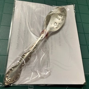 May include: A silver spoon with an ornate handle. The bowl of the spoon has the words "Coffee Now Wine Later" engraved on it.