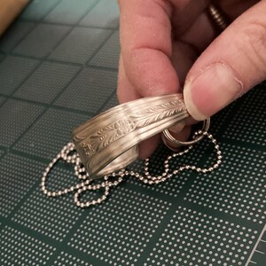 May include: A silver bracelet with an engraved floral design and a silver chain attached.