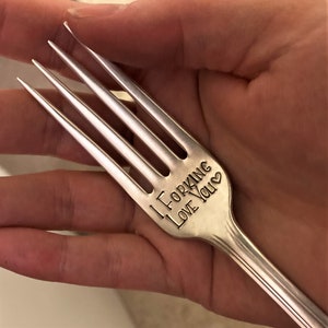 Op de afbeelding: Een zilveren vork met de woorden "I forking love you" gegraveerd op het handvat.
