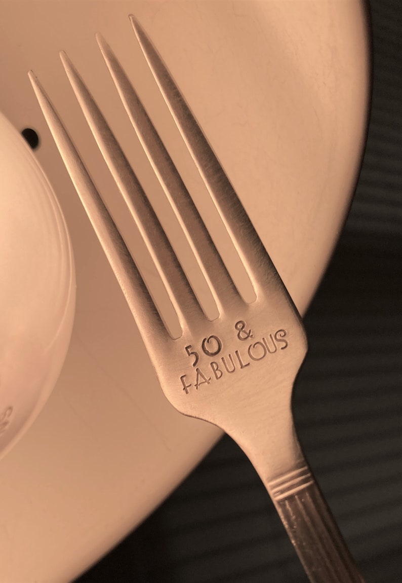 May include: Silver fork with the words "50 & FABULOUS" engraved on the handle.