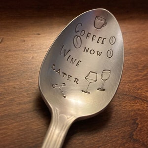 May include: A silver spoon with the text "Coffee Now Wine Later" engraved on it. The spoon also has a coffee cup, coffee beans, wine glasses, and a corkscrew engraved on it.