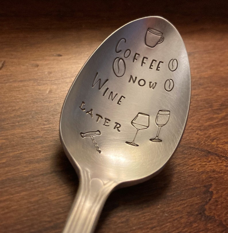 May include: A silver spoon with the text "Coffee Now Wine Later" engraved on it. The spoon also has a coffee cup, coffee beans, wine glasses, and a corkscrew engraved on it.