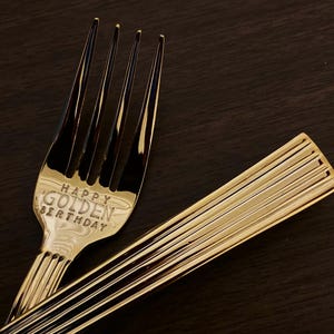 May include: Gold-colored fork with the words "Happy Golden Birthday" engraved on the handle.