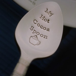 May include: A silver spoon with the words "My Hot Cocoa Spoon" engraved on it. A small illustration of a cup of hot cocoa with whipped cream is also engraved on the spoon.