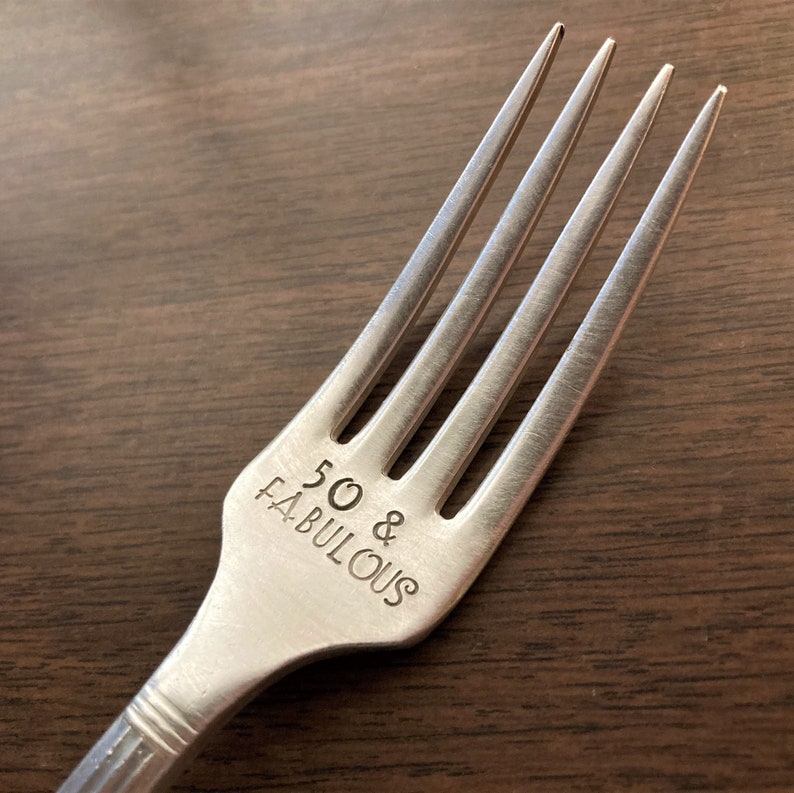 May include: Silver fork with the words "50 & Fabulous" engraved on the handle.