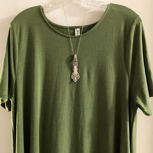 May include: A green t-shirt with a silver spoon pendant necklace.
