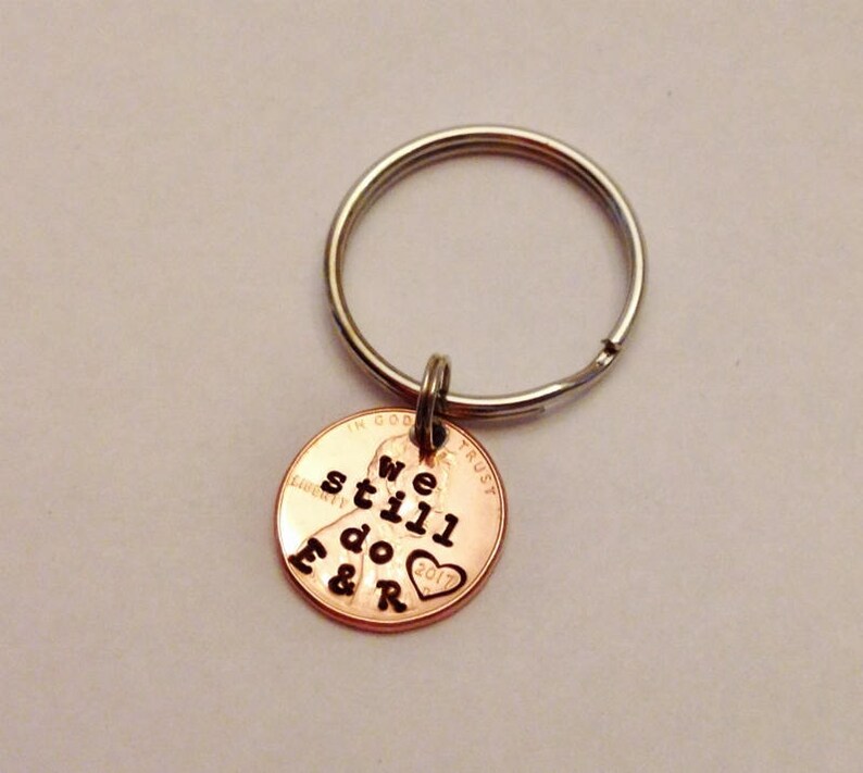 May include: A copper penny keychain with the words "We still do" and a heart with the letters "F & R" engraved on it.