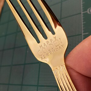 May include: A gold-colored fork with the words "Happy Golden Birthday" engraved on the handle.