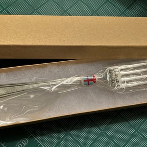 Op de afbeelding: Een zilveren vork met de woorden "Forking Love You" gegraveerd op het handvat. De vork is verpakt in een bruine kartonnen doos met wit tissuepapier.