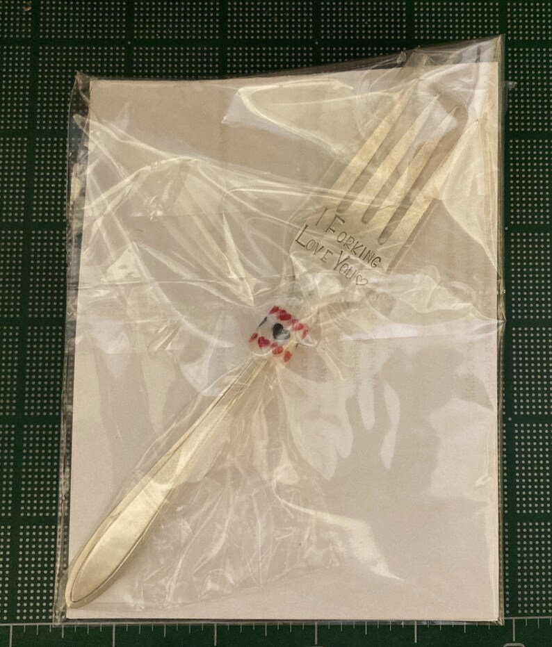 May include: A silver fork with a red and white beaded handle. The fork has the words "I ForKing Love You" engraved on the handle.