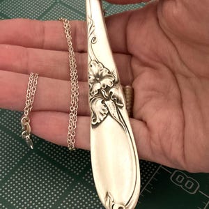 Puede incluir: Collar con colgante de cuchara de plata con detalles florales. El colgante es una cuchara reutilizada con una delicada cadena. La cuchara presenta un dise&ntilde;o floral en relieve. El collar es una joya &uacute;nica.