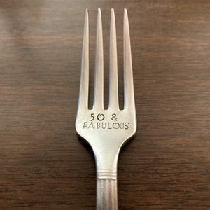 May include: A silver fork with the words "50 & FABULOUS" engraved on the handle.