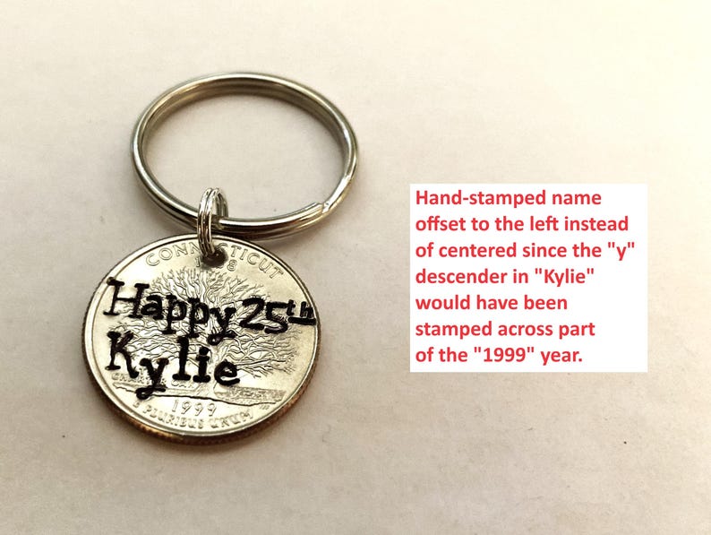 May include: A silver keychain with a coin pendant. The coin is stamped with "Happy 25th Kylie" and the year 1999. The text is in black, and the coin has a tree design. The keychain is a personalized gift.