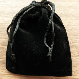May include: A black velvet drawstring pouch with a black cord.