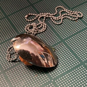 May include: A silver spoon pendant necklace with a silver chain. The spoon is shaped like a heart and has a shiny finish.