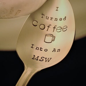 Pu&ograve; includere: Un cucchiaio in acciaio inossidabile con le parole "I Turned Coffee Into An MSW" incise nella coppetta. Un piccolo disegno di una tazza di caff&egrave; &egrave; anch'esso inciso nel cucchiaio. Il cucchiaio &egrave; angolato, con uno sfondo sfocato.