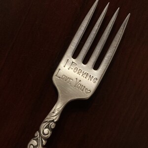 May include: A silver fork with a decorative handle engraved with the words "I Forking Love You" and a small heart.