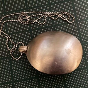 May include: A silver spoon pendant on a silver chain. The spoon is smooth and shiny, and the chain is made of small, round links.