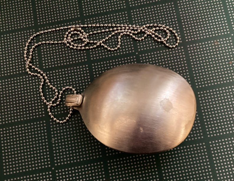 May include: A silver spoon pendant on a silver chain. The spoon is smooth and shiny, and the chain is made of small, round links.