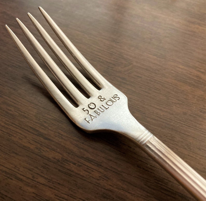 May include: Silver fork with the words "50 & FABULOUS" engraved on the handle.