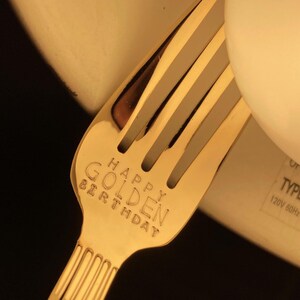 May include: Gold-colored fork with the words "Happy Golden Birthday" engraved on the handle.