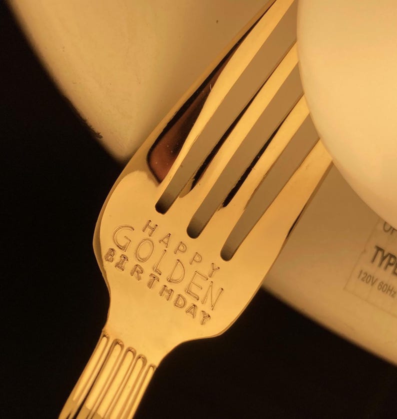 May include: Gold-colored fork with the words "Happy Golden Birthday" engraved on the handle.