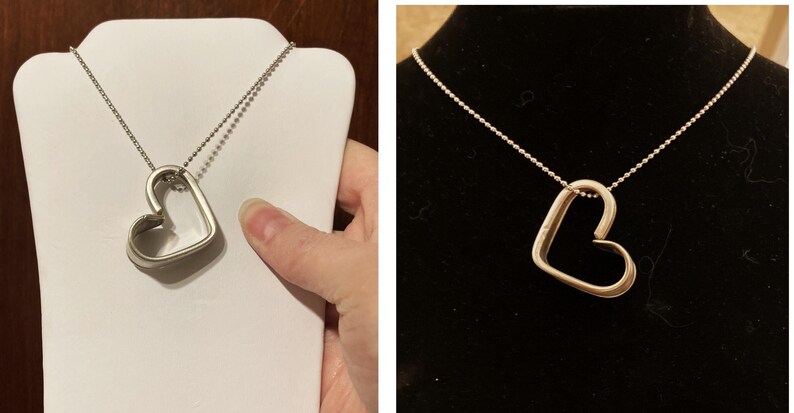 May include: A silver necklace with a heart-shaped pendant. The pendant is open and has a smooth, polished finish.