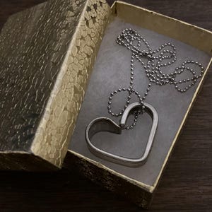 May include: A silver heart-shaped pendant necklace with a ball chain in a gold gift box.