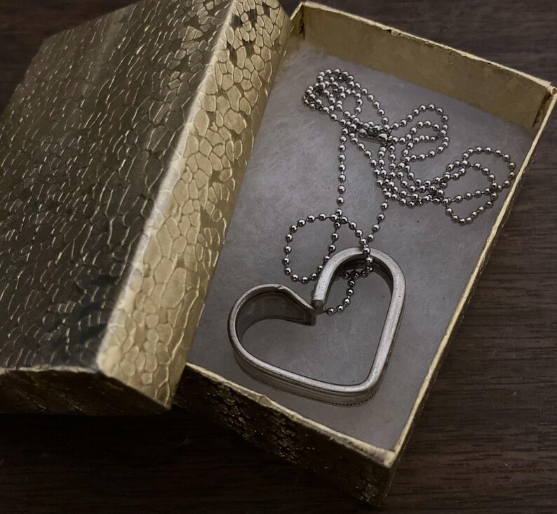 May include: A silver heart-shaped pendant necklace with a ball chain in a gold gift box.