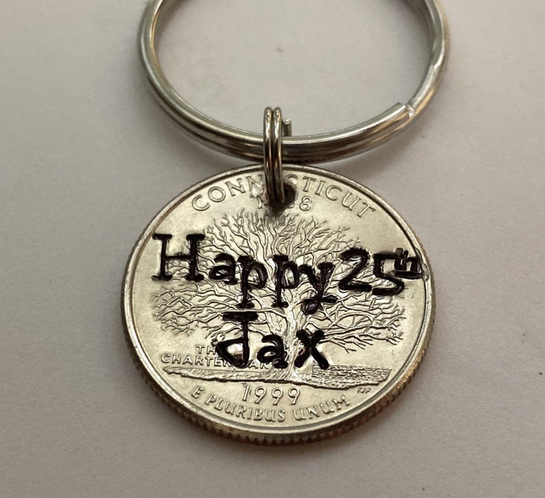 May include: A silver keychain with a Connecticut quarter coin pendant. The coin is engraved with "Happy 25th Jax" and the year 1999. The keychain has a silver ring.