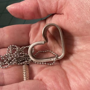 May include: A silver heart-shaped pendant necklace with a delicate chain.