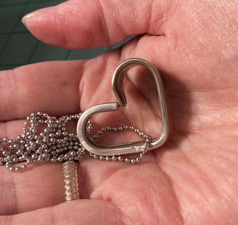 May include: A silver heart-shaped pendant necklace with a delicate chain.