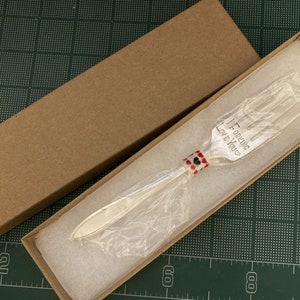 May include: A silver fork with a red and black beaded handle in a brown box. The fork has the words "I Forking Love You" engraved on it.