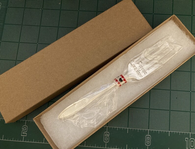 May include: A silver fork with a red and black beaded handle in a brown box. The fork has the words "I Forking Love You" engraved on it.
