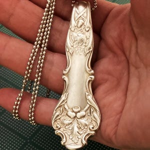 Puede incluir: Un collar de plata con un colgante hecho de una cuchara de plata vintage. La cuchara est&aacute; decorada con un dise&ntilde;o de hoja de roble y bellota.