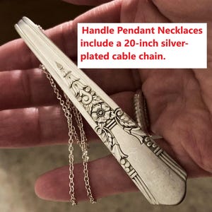 May include: Silver-plated handle pendant necklace featuring floral and geometric patterns. The necklace has a 50.8 cm cable chain. The pendant is a repurposed utensil, with an ornate design.