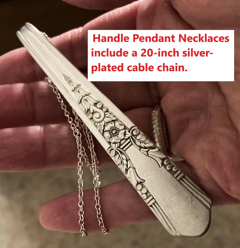 May include: Silver-plated handle pendant necklace featuring floral and geometric patterns. The necklace has a 50.8 cm cable chain. The pendant is a repurposed utensil, with an ornate design.