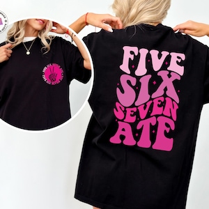 May include: Black t-shirt with a pink and white gradient graphic that says "FIVE SIX SEVEN ATE" on the back.