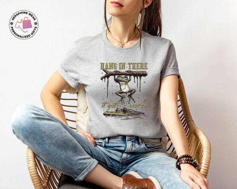 May include: A gray t-shirt with a graphic of a frog hanging on a branch with the text "Hang in there it gets worse".