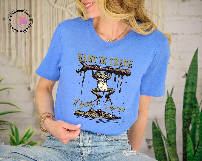 May include: A blue t-shirt with a graphic of a frog hanging on a branch with the text "Hang in there it gets worse".