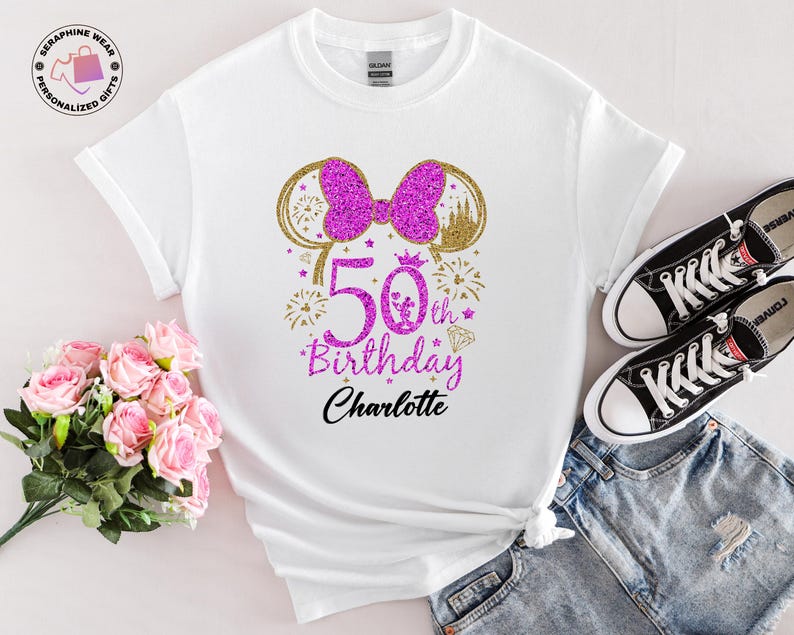Puede incluir: Camiseta blanca con un lazo rosa brillante y un dise&ntilde;o de orejas de rat&oacute;n doradas. La camiseta presenta el texto "50th Birthday Charlotte" en rosa y negro, con fuegos artificiales y un diamante. Zapatillas Converse negras y pantalones cortos vaqueros tambi&eacute;n en la imagen.