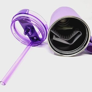May include: A lavender-colored stainless steel tumbler with a matching handle and lid. The lid is transparent with a purple straw. The tumbler is open, revealing the interior and a few folded papers.