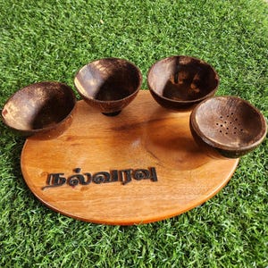 May include: A wooden serving tray with four small coconut shell bowls. The tray has the Tamil word "தல்லாடி" engraved on it.