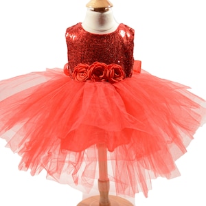 May include: A red tulle dress with a sequined bodice and a flower embellishment around the waist.