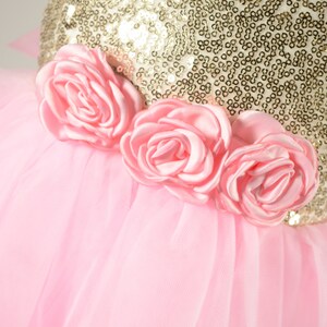 Op de afbeelding: Een roze tule rok met een gouden pailletten lijfje en drie roze satijnen rozen.